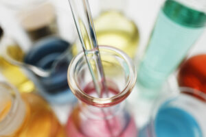pipette in laboratory flask containing transition metal salts